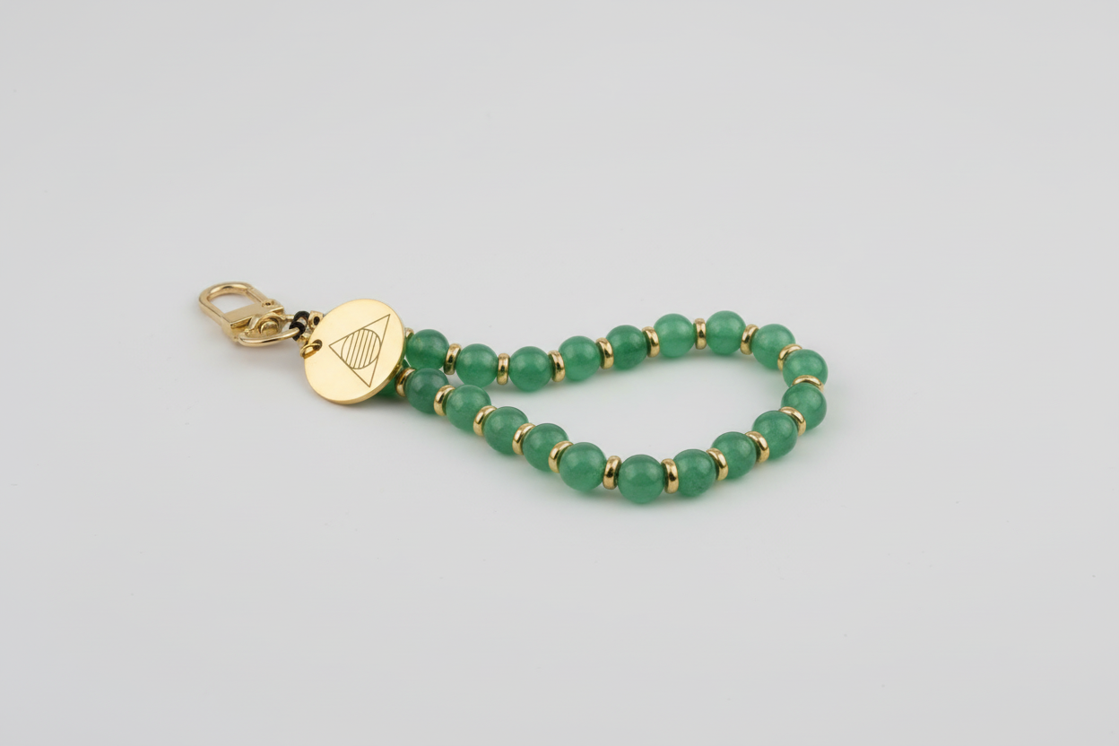 Green beaded bracelet with a gold clasp on a stone surface