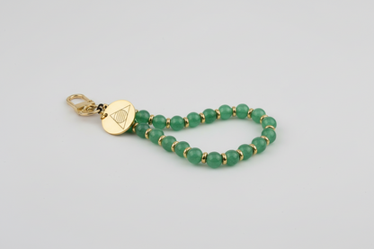 Green beaded bracelet with a gold clasp on a stone surface
