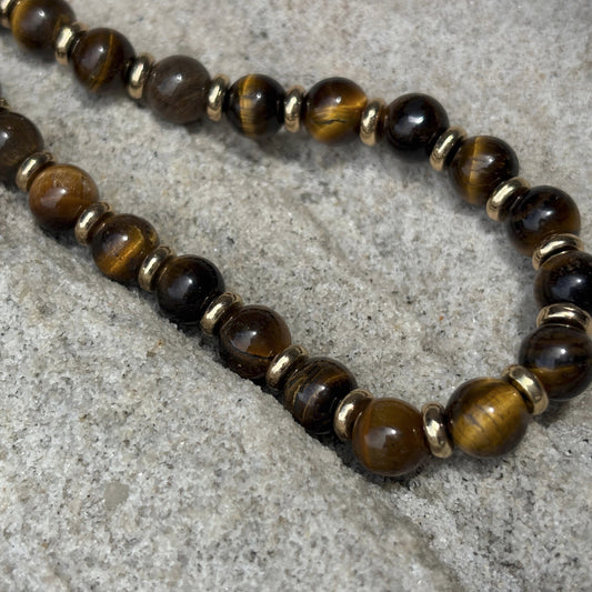 Beaded tiger eye stone phone chain on a textured surface