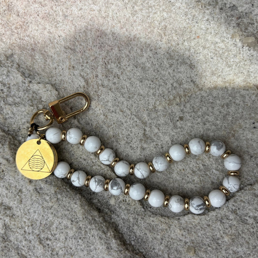 Beaded keychain with gold tag on stone surface